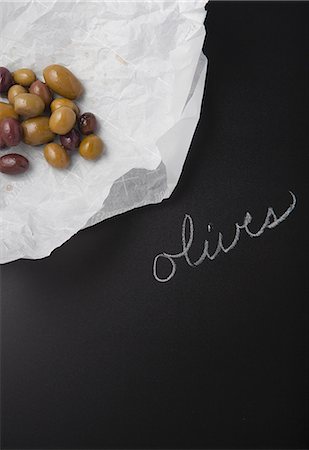 Olives on a piece of paper on a slate surface with a label Stock Photo - Premium Royalty-Free, Code: 659-08147216