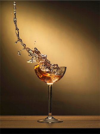 simsearch:659-07958903,k - A cocktail splashing out of a glass with ice cubes Stock Photo - Premium Royalty-Free, Code: 659-08147282