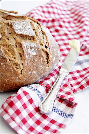 fat (food substance) - Crusty bread and a knife with butter on a checked cloth Stock Photo - Premium Royalty-Free, Code: 659-08147366