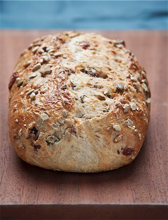 pão de milho - A loaf of country bread with seeds on a wooden board Foto de stock - Royalty Free Premium, Número: 659-08147418