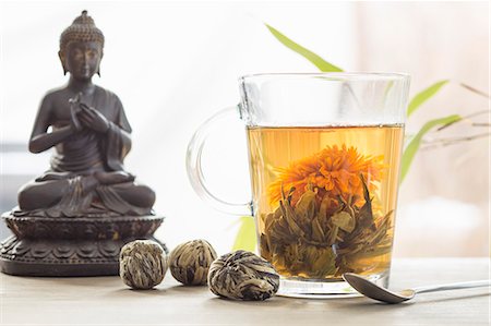 A glass of floral tea, closed flowers and a Buddha figure Stockbilder - Premium RF Lizenzfrei, Bildnummer: 659-08147486