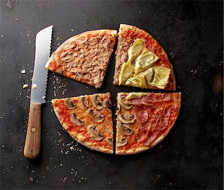 simsearch:659-08147619,k - A pizza with tuna, mushrooms, Parma ham and artichokes, sliced Photographie de stock - Premium Libres de Droits, Code: 659-08147620