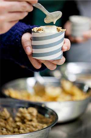 frühstücksbüffet - A person at a breakfast buffet pouring vegan sauce onto muesli in a paper tub Stockbilder - Premium RF Lizenzfrei, Bildnummer: 659-08147717