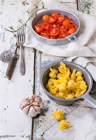 simsearch:659-08940783,k - Sacchettini with baked tomatoes and garlic on an old wooden table Stock Photo - Premium Royalty-Free, Code: 659-08148136