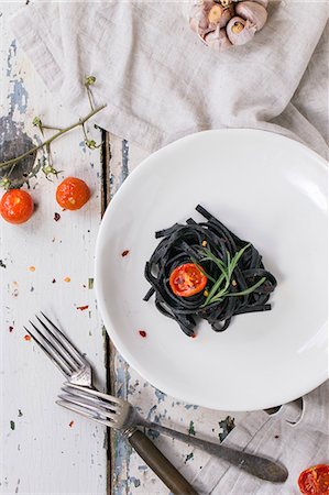 shabby - Black tagliolini with baked tomatoes and garlic on old wooden table Stock Photo - Premium Royalty-Free, Code: 659-08148138