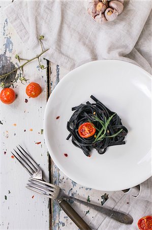 Black tagliolini with baked tomatoes and garlic on old wooden table Foto de stock - Sin royalties Premium, Código: 659-08148138