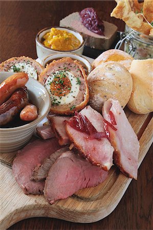 A ploughman's lunch featuring ham, sausages, Scotch eggs, chutney and bread rolls (England) Photographie de stock - Premium Libres de Droits, Code: 659-08148176
