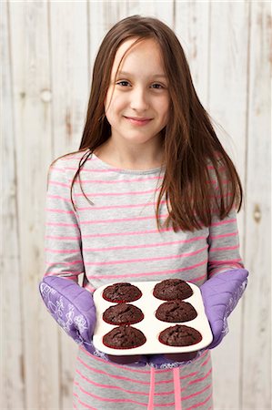 A girl holding freshly baked chocolate cupcakes Foto de stock - Sin royalties Premium, Código: 659-08418891