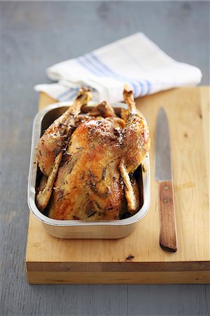 simsearch:659-06902078,k - Roast chicken in a metal dish on a wooden chopping board Photographie de stock - Premium Libres de Droits, Code: 659-08419103