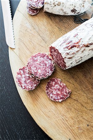 Sliced hard sausages on a wooden plate Photographie de stock - Premium Libres de Droits, Code: 659-08419260