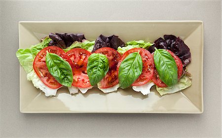 Batavia lettuce leaves topped with tomato and basil Stock Photo - Premium Royalty-Free, Code: 659-08419330