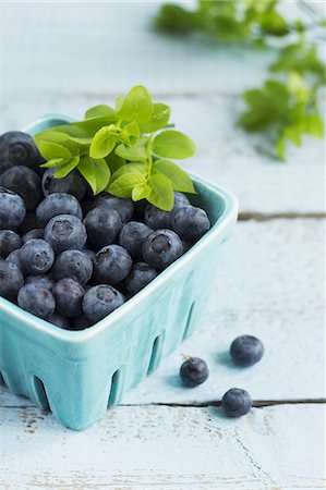 Blueberries with leaves in a turquoise punnet Stock Photo - Premium Royalty-Free, Code: 659-08419390