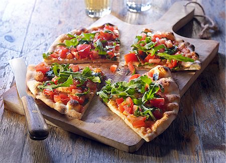 simsearch:659-07959236,k - Pizza bread with tomatoes and rocket, sliced on a wooden board Stock Photo - Premium Royalty-Free, Code: 659-08419392