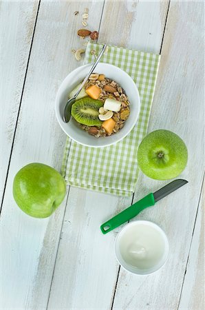 A healthy breakfast: muesli with fresh fruits, nuts and milk, kiwi, apple and melon on a wooden table Foto de stock - Sin royalties Premium, Código: 659-08419701