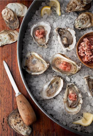 Oysters in shells on a bed of salt with lemon wedges and a Mignonette sauce Stock Photo - Premium Royalty-Free, Code: 659-08419753