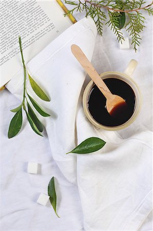 simsearch:659-06495358,k - Black coffee and a cop with a wooden spoon with sugar cubes and leaves next to it Stock Photo - Premium Royalty-Free, Code: 659-08512802