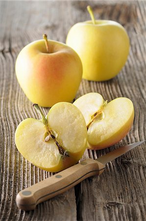 simsearch:659-06494827,k - Golden Delicious apples, whole and halved, on a wooden surface Foto de stock - Sin royalties Premium, Código: 659-08512845