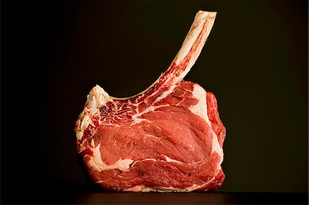 Rib-eye steak with a long bone on a dark surface Foto de stock - Sin royalties Premium, Código: 659-08513047