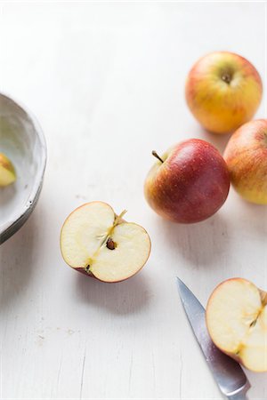 simsearch:659-03524204,k - Apples on a white surface with a halved apple and a knife Foto de stock - Sin royalties Premium, Código: 659-08513131