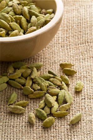 elettaria cardamomum - Cardamom pods in a wooden bowl and in front of it Stock Photo - Premium Royalty-Free, Code: 659-08513162