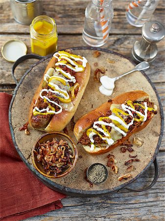 Chilli hot dogs topped with fried onion, mustard and mayonaise Foto de stock - Sin royalties Premium, Código: 659-08895674