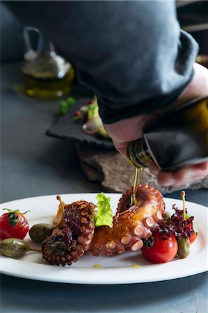 sepia toned - Olive oil being poured on octopus with tomatoes and giant capers Stock Photo - Premium Royalty-Free, Code: 659-08895839