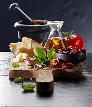 An arrangement of tomatoes, olive oil, parmesan, garlic, pine nuts and basil on a chopping board Photographie de stock - Premium Libres de Droits, Code: 659-08895908