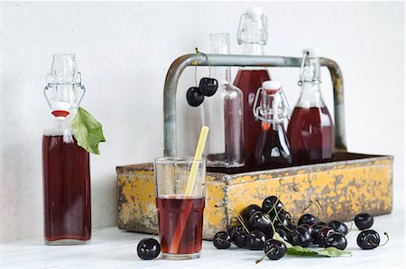 Cherry juice in a glass with a straw, bottles in a bottle carrier and fresh cherries Foto de stock - Sin royalties Premium, Código: 659-08895901