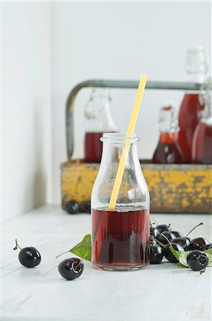 Cherry juice in a glass bottle with a straw, bottles in a bottle carrier and fresh cherries Stock Photo - Premium Royalty-Free, Code: 659-08895902