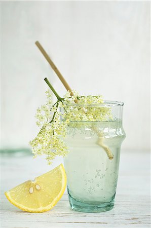 simsearch:659-08906339,k - An elderflower drink in a glass with a straw, elderflowers and a wedge of lemon Stock Photo - Premium Royalty-Free, Code: 659-08896094