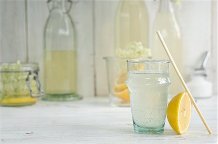 An elderflower drink in a glass with a straw and homemade elderflower cordial in bottles Stock Photo - Premium Royalty-Free, Code: 659-08896093