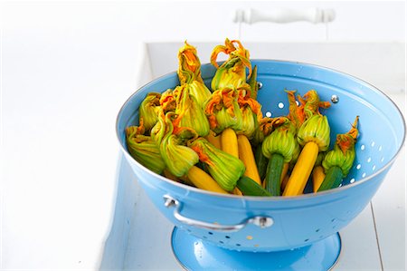 Green and yellow courgettes with flowers in a blue enamel colander Foto de stock - Sin royalties Premium, Código: 659-08896191