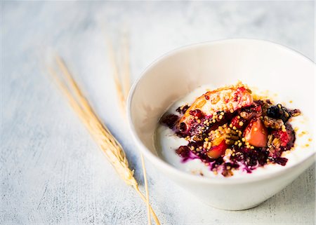 A bowl of Greek yoghurt topped with baked slices of apple with quinoa, oats, pecan nuts and berries Stock Photo - Premium Royalty-Free, Code: 659-08896356