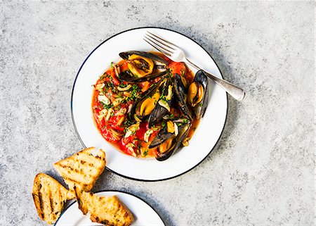 simsearch:659-08939995,k - Steamed New England mussels in stewed tomatoes served with a side of grilled sour dough bread Foto de stock - Royalty Free Premium, Número: 659-08896363