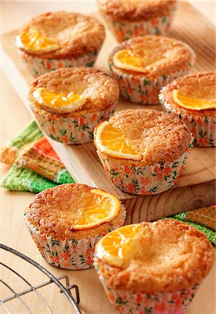 simsearch:659-07028021,k - Deveral orange and semolina muffins on a wooden board sitting on a wooden table top. Photographie de stock - Premium Libres de Droits, Code: 659-08896731