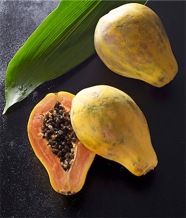 simsearch:659-08897144,k - Two papayas, one halved, with a palm leaf Photographie de stock - Premium Libres de Droits, Code: 659-08897019