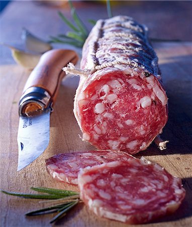 A sliced French salami and an Opinel knife on a wooden board Foto de stock - Sin royalties Premium, Código: 659-08897022