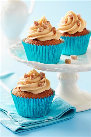 Sticky toffee cupcakes with caramel icing and fudge pieces in blue metalic cupcake cases Stock Photo - Premium Royalty-Free, Code: 659-08897071