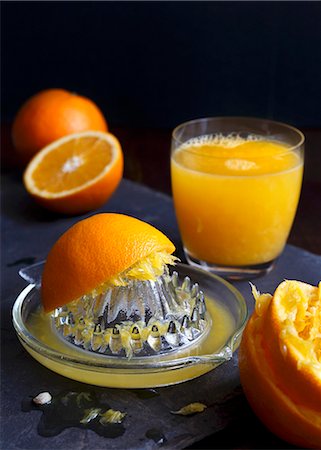 simsearch:659-08896969,k - Manual glass juicet extractor with squeezed oranges and a glass of orange juice on a dark slate Stock Photo - Premium Royalty-Free, Code: 659-08897134