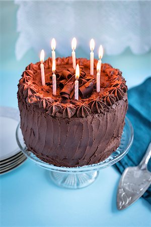 Chocolate birthday cake with 8 lit candles on cake stand Stock Photo - Premium Royalty-Free, Code: 659-08897218