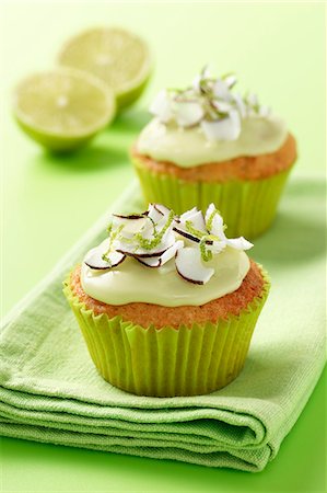 simsearch:659-07958615,k - Fresh coconut and lime iced cupcakes on a green napkin and green background with 2 half limes Foto de stock - Sin royalties Premium, Código: 659-08897306