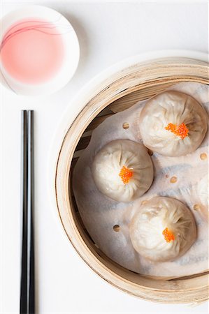 Steamed Chinese dumplings with fish roe in bamboo steaming basket with chopsticks and dipping sauce Stock Photo - Premium Royalty-Free, Code: 659-08897345