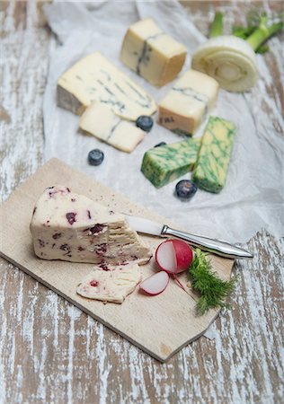 Wensleydale, Jacobean sage, Cambozola, Morbier with fennel, radishes and blueberries on a wooden board and a piece of paper Stock Photo - Premium Royalty-Free, Code: 659-08904083