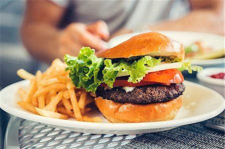 A cheeseburger and chips on a table in a restaurant Stock Photo - Premium Royalty-Free, Code: 659-08904123