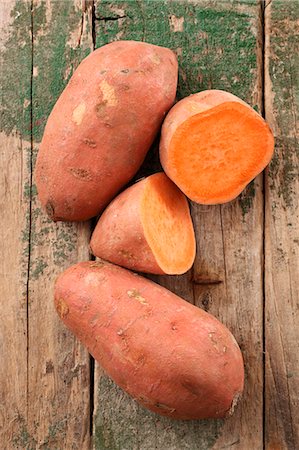Sweet potatoes, whole and halved, on a wooden surface Stock Photo - Premium Royalty-Free, Code: 659-08904316