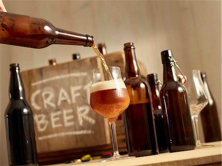 simsearch:659-03527532,k - Beer being poured with open bottles of beer and a wooden crate labelled 'Craft Beer' in the background Foto de stock - Sin royalties Premium, Código: 659-08904463