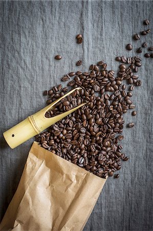 simsearch:659-08904387,k - Coffee beans spilling from a paper bag with a bamboo scoop on a grey linen cloth Photographie de stock - Premium Libres de Droits, Code: 659-08904588