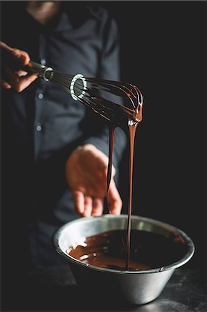 Liquid chocolate dripping from a whisk into a stainless steel bowl Stock Photo - Premium Royalty-Free, Code: 659-08904605