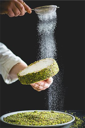 pastrycook - A confectioner dusting a small pistachio cake with icing sugar Stock Photo - Premium Royalty-Free, Code: 659-08904630