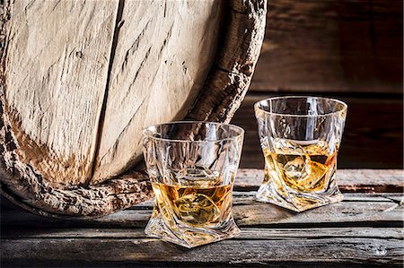 Two glasses of whiskey on the rocks in front of an old wooden barrel Stock Photo - Premium Royalty-Free, Code: 659-08904761